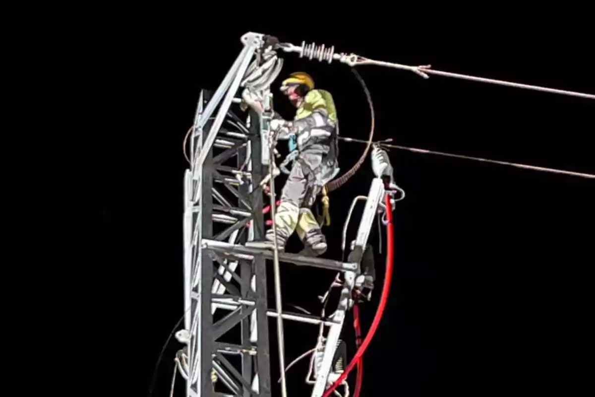Trabajador con casco y equipo de seguridad realizando labores en una torre eléctrica durante la noche Trabajador con casco y equipo de seguridad realizando labores en una torre eléctrica durante la noche