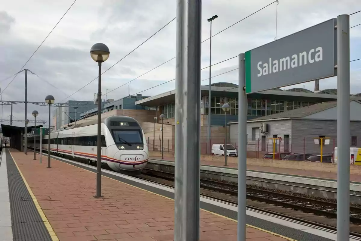 Un tren de Renfe detenido en la estación de Salamanca junto a un andén y un cartel que indica el nombre de la ciudad Un tren de Renfe detenido en la estación de Salamanca junto a un andén y un cartel que indica el nombre de la ciudad