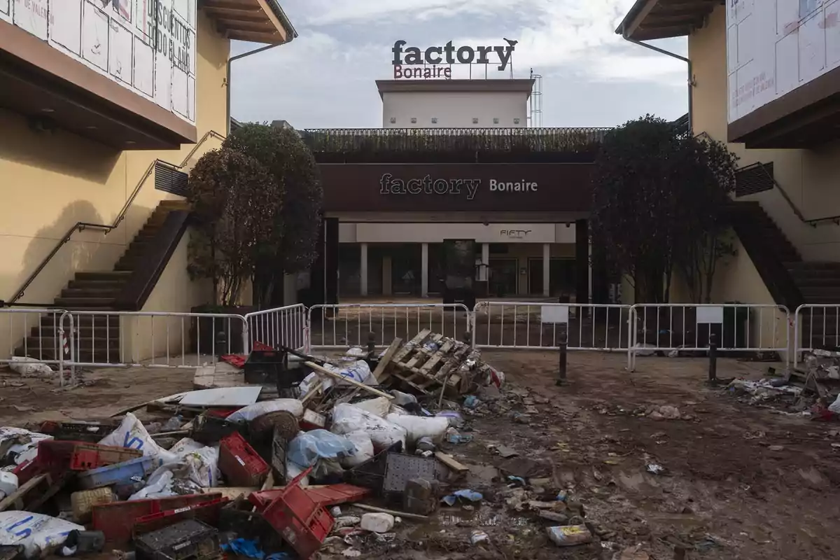 Entrada de un centro comercial con basura y escombros en el suelo, vallas de seguridad y aspecto descuidado Entrada de un centro comercial con basura y escombros en el suelo, vallas de seguridad y aspecto descuidado