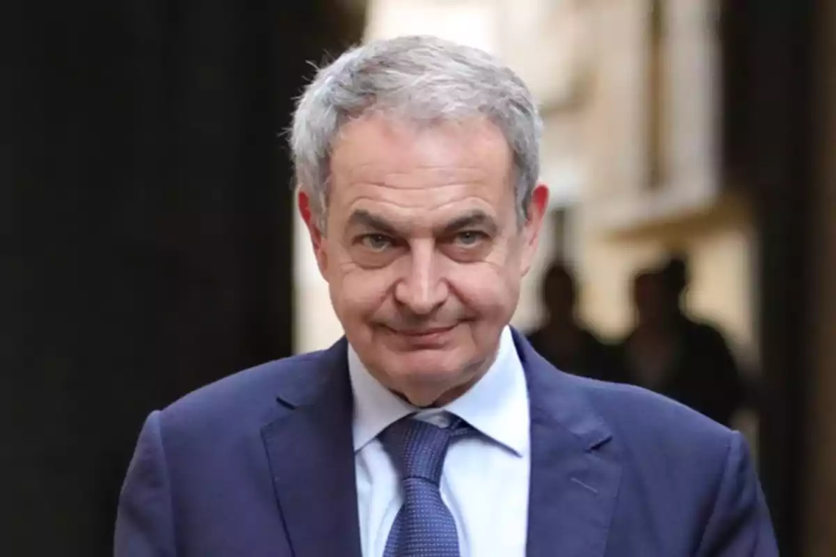 Hombre de cabello canoso con traje azul y corbata caminando en un entorno urbano desenfocado Hombre de cabello canoso con traje azul y corbata caminando en un entorno urbano desenfocado