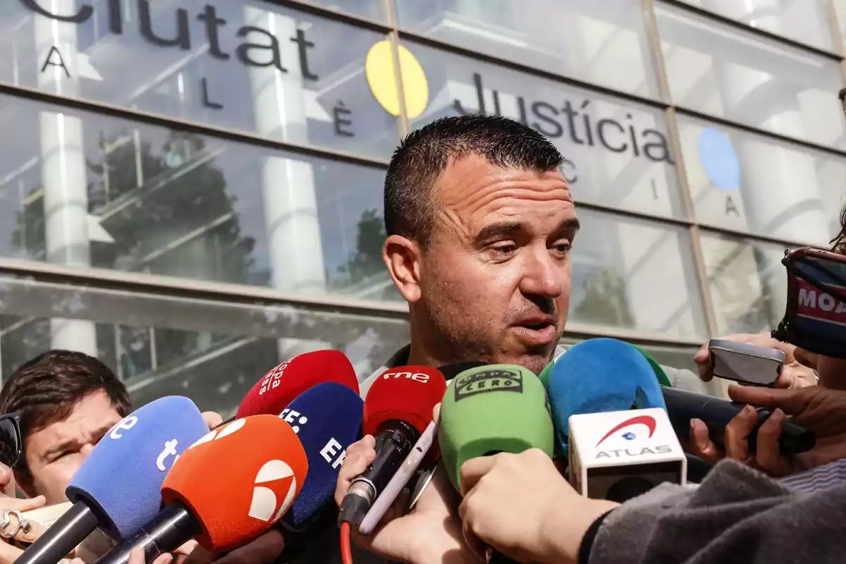 Un hombre rodeado de micrófonos de diferentes medios de comunicación da declaraciones frente a un edificio de justicia Un hombre rodeado de micrófonos de diferentes medios de comunicación da declaraciones frente a un edificio de justicia