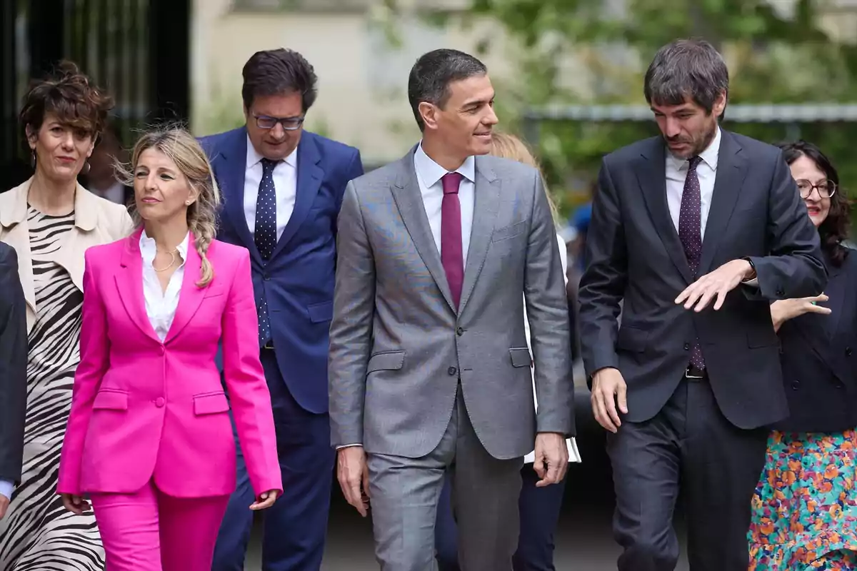 Grupo de personas vestidas de manera formal caminando al aire libre en un entorno urbano
