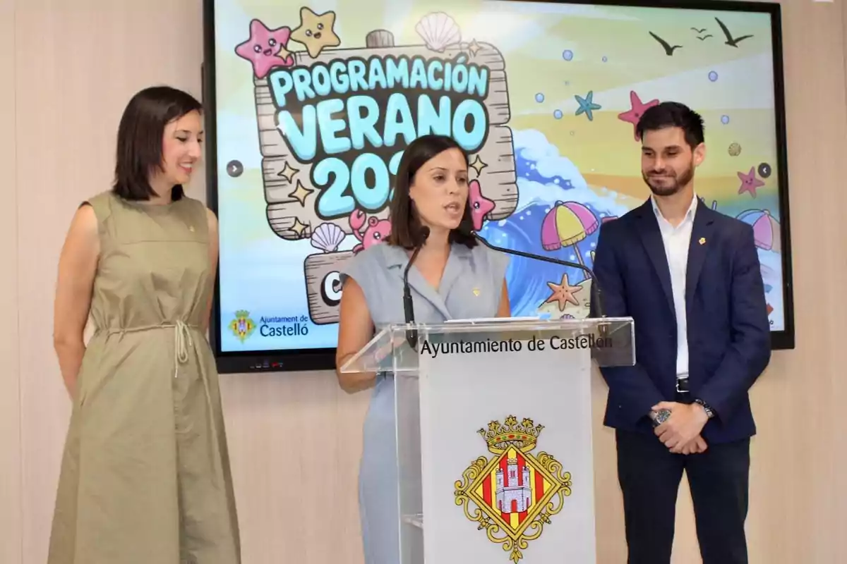Tres personas presentan la programación de verano 2024 del Ayuntamiento de Castelló frente a un atril y una pantalla con ilustraciones veraniegas.