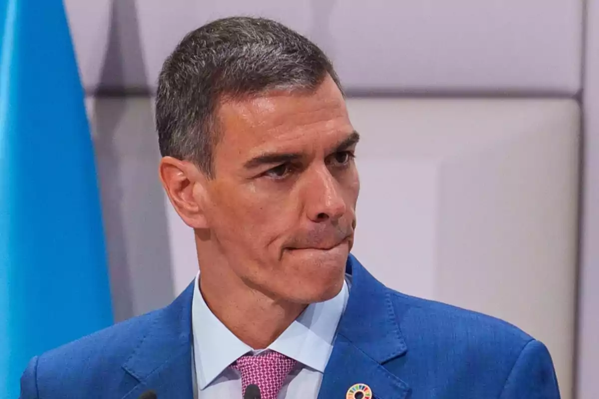 Hombre de cabello corto y canoso con traje azul y corbata rosa mirando hacia un lado con expresión seria Hombre de cabello corto y canoso con traje azul y corbata rosa mirando hacia un lado con expresión seria