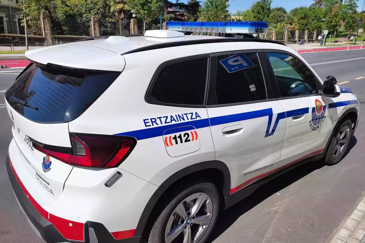 Coche patrulla de la Ertzaintza estacionado en una calle junto a una acera Coche patrulla de la Ertzaintza estacionado en una calle junto a una acera