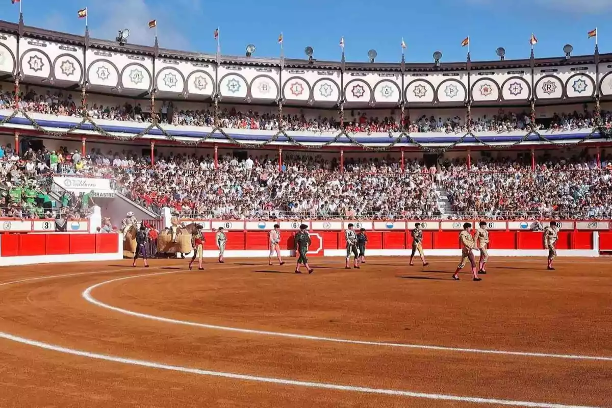Plaza de toros llena de espectadores con toreros y picadores en el ruedo durante una corrida bajo un cielo despejado Plaza de toros llena de espectadores con toreros y picadores en el ruedo durante una corrida bajo un cielo despejado