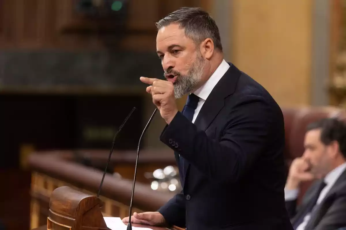 Hombre de traje hablando con gesto enfático en un parlamento Hombre de traje hablando con gesto enfático en un parlamento