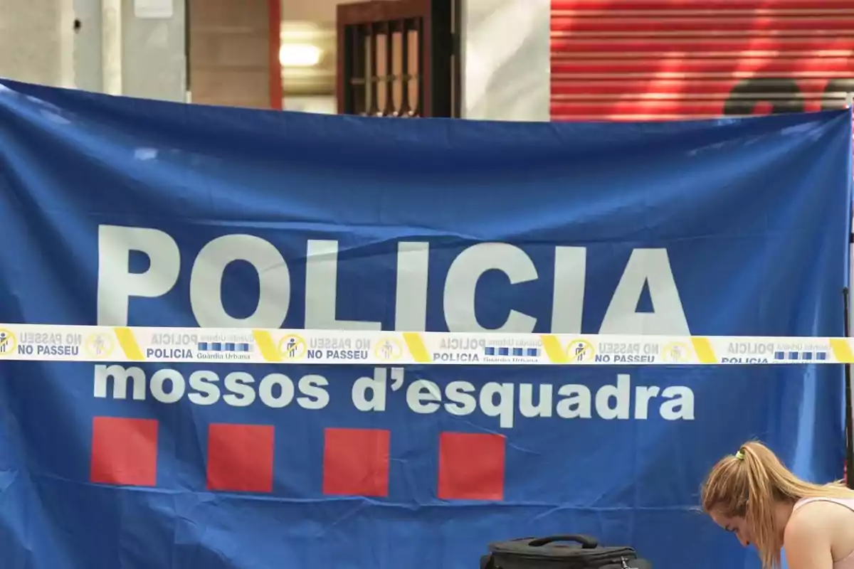 Cinta policial de los Mossos d'Esquadra acordonando una zona con una mujer agachada en primer plano