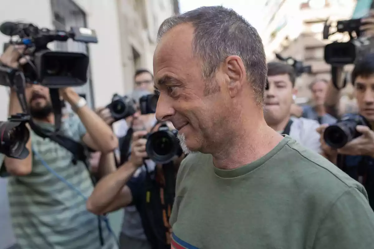 Hombre de perfil con camiseta verde rodeado de fotógrafos y cámaras en una calle concurrida Hombre de perfil con camiseta verde rodeado de fotógrafos y cámaras en una calle concurrida