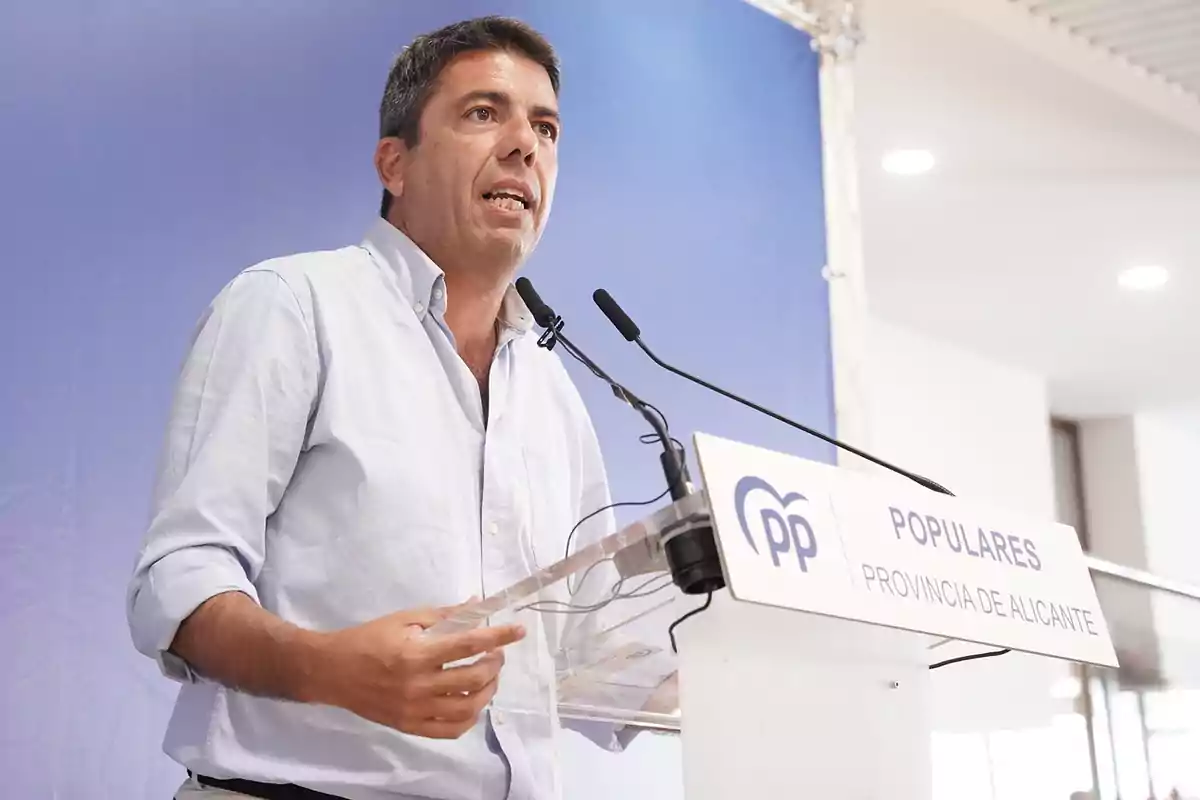 Hombre hablando en un atril con micrófonos en un evento del Partido Popular de la provincia de Alicante