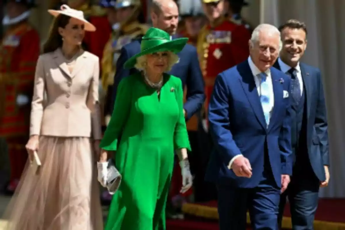 Grupo de personas elegantemente vestidas, que son la Familia Real británica junto a Emmanuel Macron, caminando al aire libre durante un evento formal. Grupo de personas elegantemente vestidas, que son la Familia Real británica junto a Emmanuel Macron, caminando al aire libre durante un evento formal.