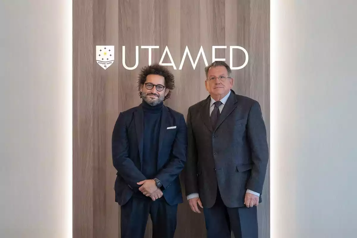 Dos hombres posan juntos frente a una pared de madera con el logotipo de UTAMED