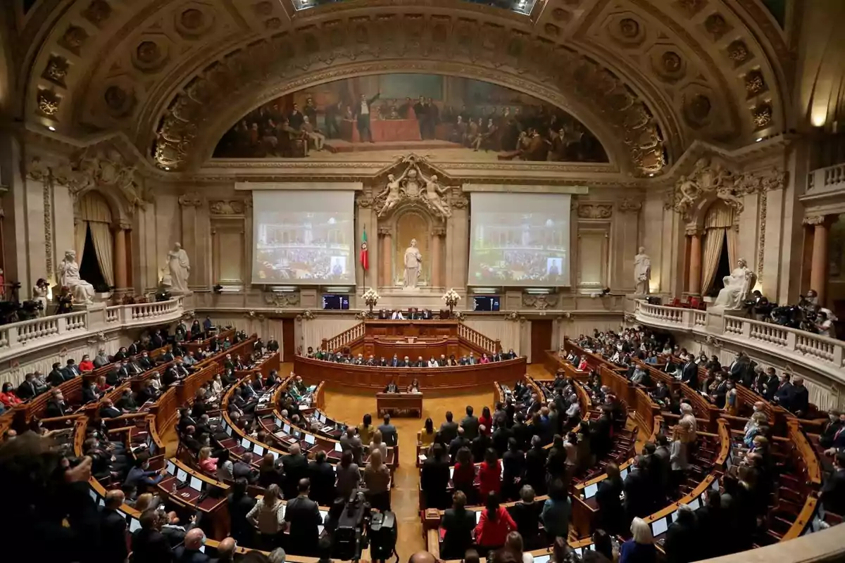 Vista panorámica de un parlamento europeo con arquitectura clásica, techos decorados, estatuas y muchas personas sentadas en bancas semicirculares
