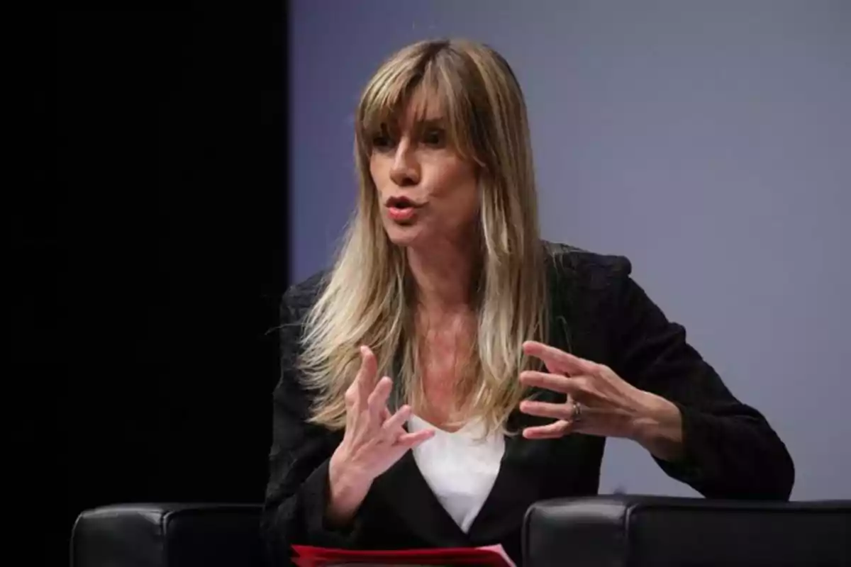 Mujer de cabello largo y rubio hablando y gesticulando con las manos durante una conferencia o entrevista Mujer de cabello largo y rubio hablando y gesticulando con las manos durante una conferencia o entrevista