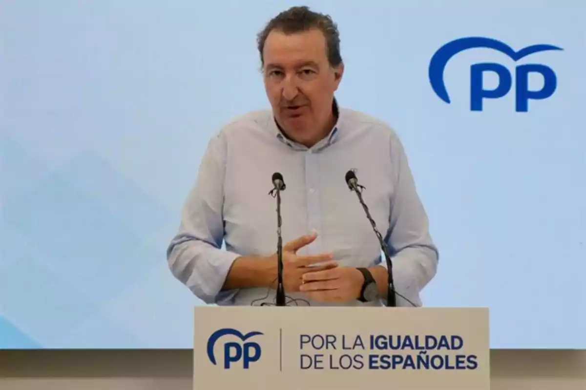 Hombre de cabello corto y camisa clara hablando en un atril con el logotipo del Partido Popular y el texto por la igualdad de los españoles Hombre de cabello corto y camisa clara hablando en un atril con el logotipo del Partido Popular y el texto por la igualdad de los españoles