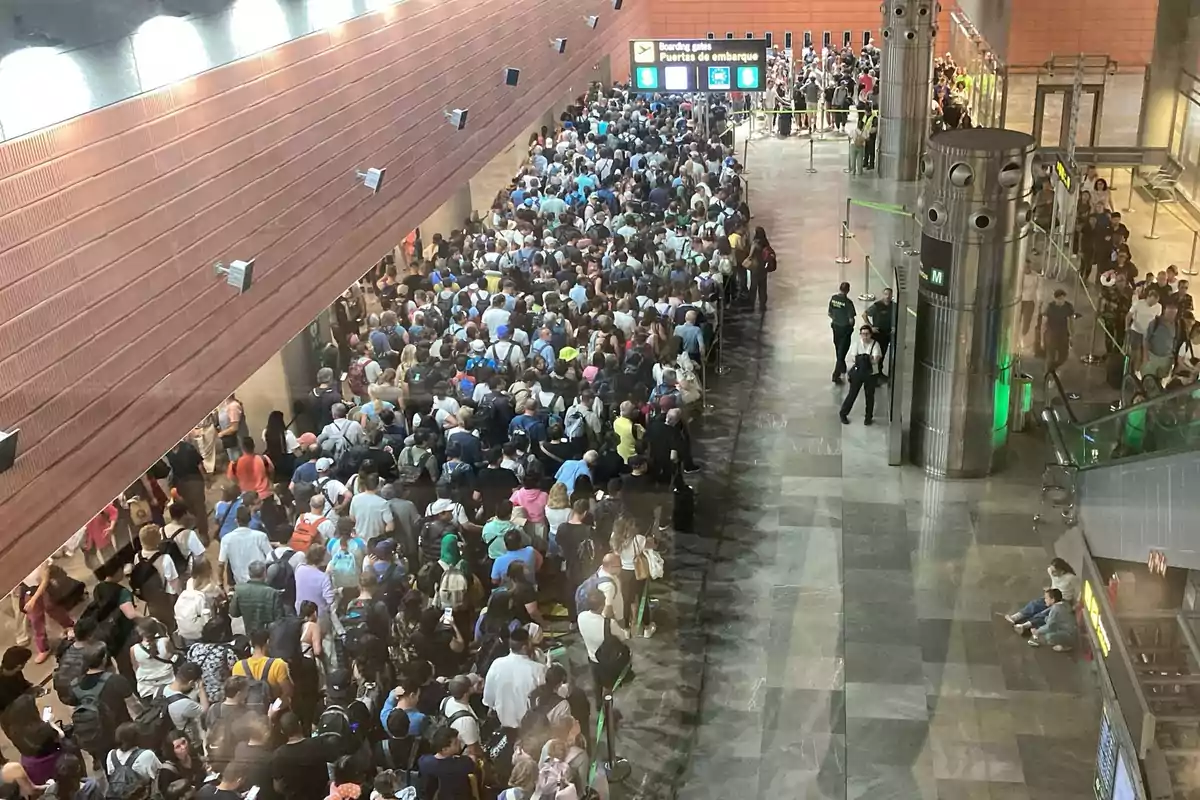 Gran cantidad de personas haciendo fila en una terminal de aeropuerto mientras esperan pasar por el control de seguridad Gran cantidad de personas haciendo fila en una terminal de aeropuerto mientras esperan pasar por el control de seguridad