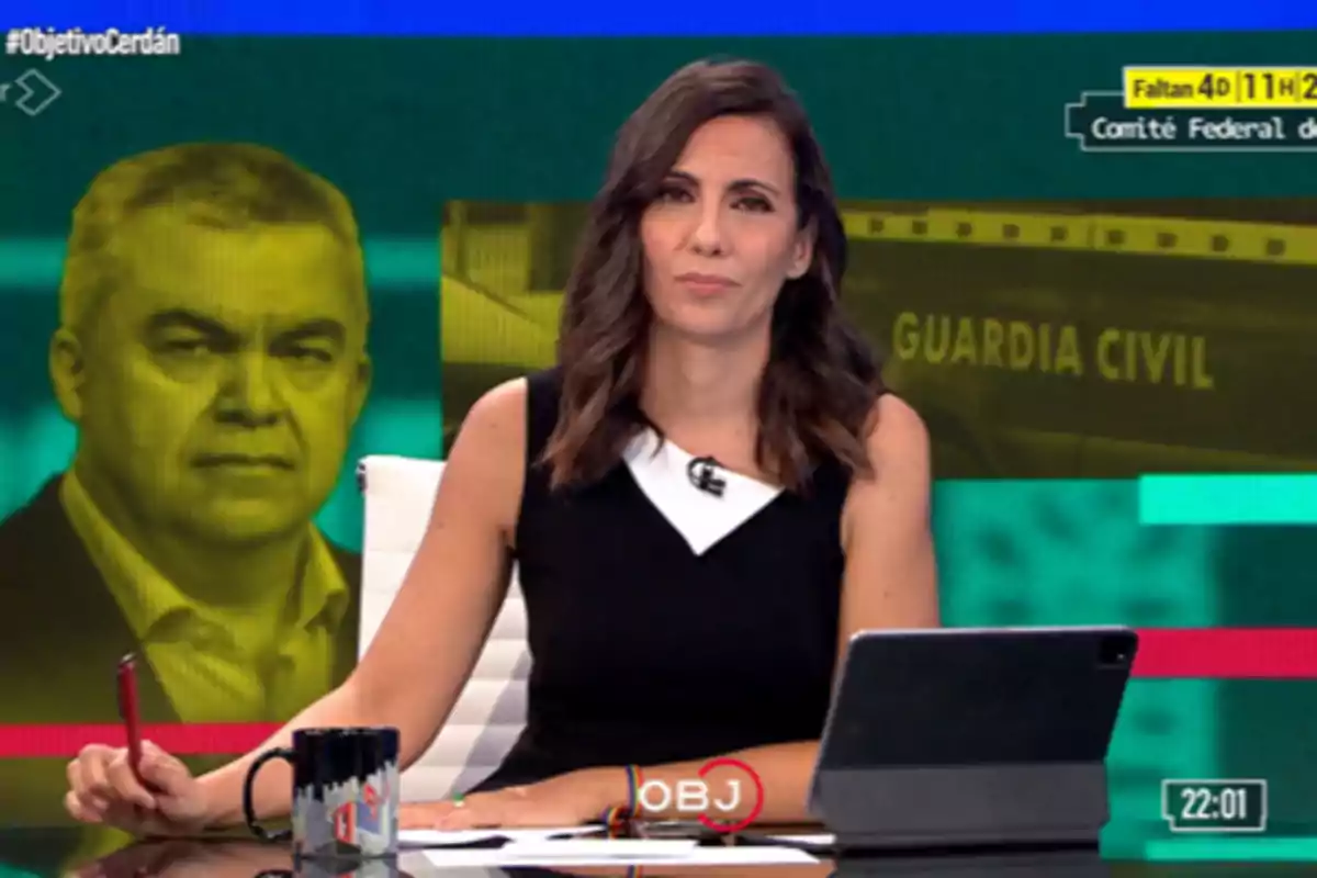 Presentadora de noticias sentada en un escritorio con una tableta y una taza, al fondo una pantalla muestra el rostro de un hombre en tonos amarillos y el texto Guardia Civil Presentadora de noticias sentada en un escritorio con una tableta y una taza, al fondo una pantalla muestra el rostro de un hombre en tonos amarillos y el texto Guardia Civil