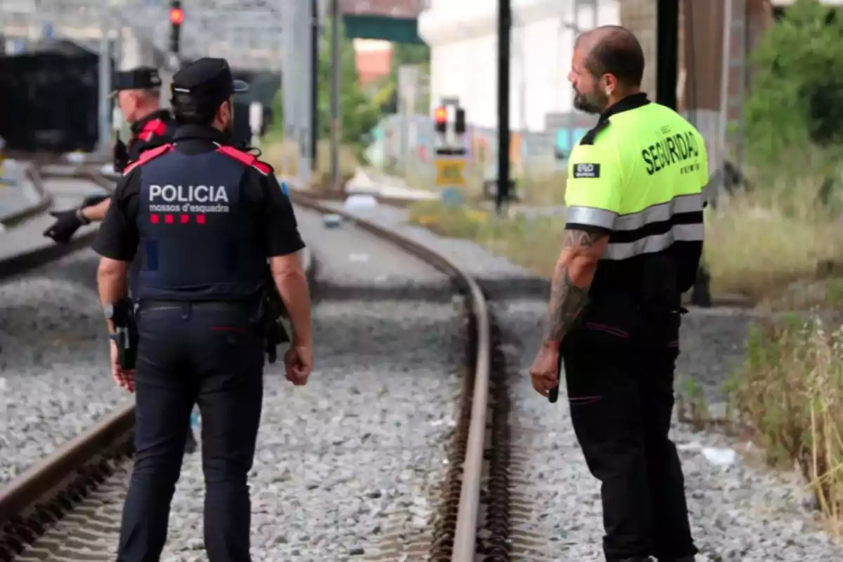 Un policía y un guardia de seguridad conversan junto a unas vías de tren Un policía y un guardia de seguridad conversan junto a unas vías de tren