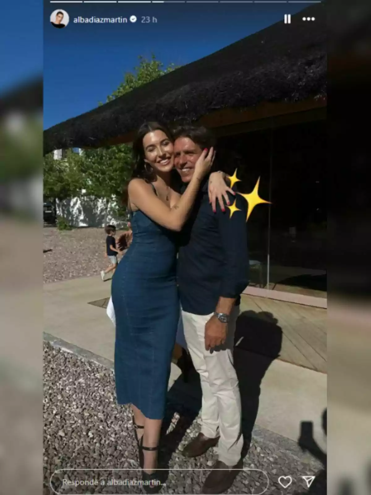 Una mujer con vestido de mezclilla, que es Alba Díaz, abraza y sonríe junto a un hombre vestido con camisa azul y pantalón claro, que es Manuel Díaz, al aire libre en un día soleado. Una mujer con vestido de mezclilla, que es Alba Díaz, abraza y sonríe junto a un hombre vestido con camisa azul y pantalón claro, que es Manuel Díaz, al aire libre en un día soleado.