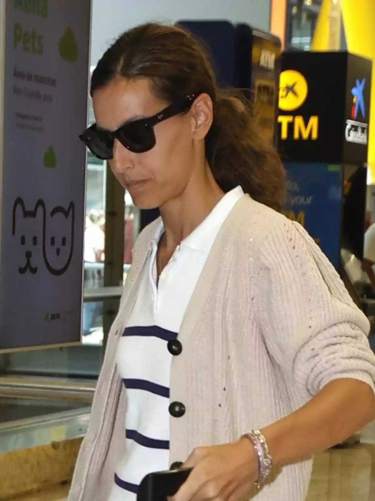 Ana Boyer con gafas de sol y suéter beige caminando en un aeropuerto Ana Boyer con gafas de sol y suéter beige caminando en un aeropuerto