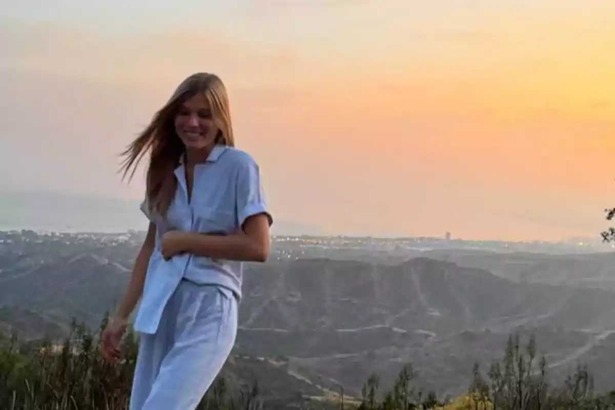 Smiling young man in light clothing standing in a mountainous landscape at sunset