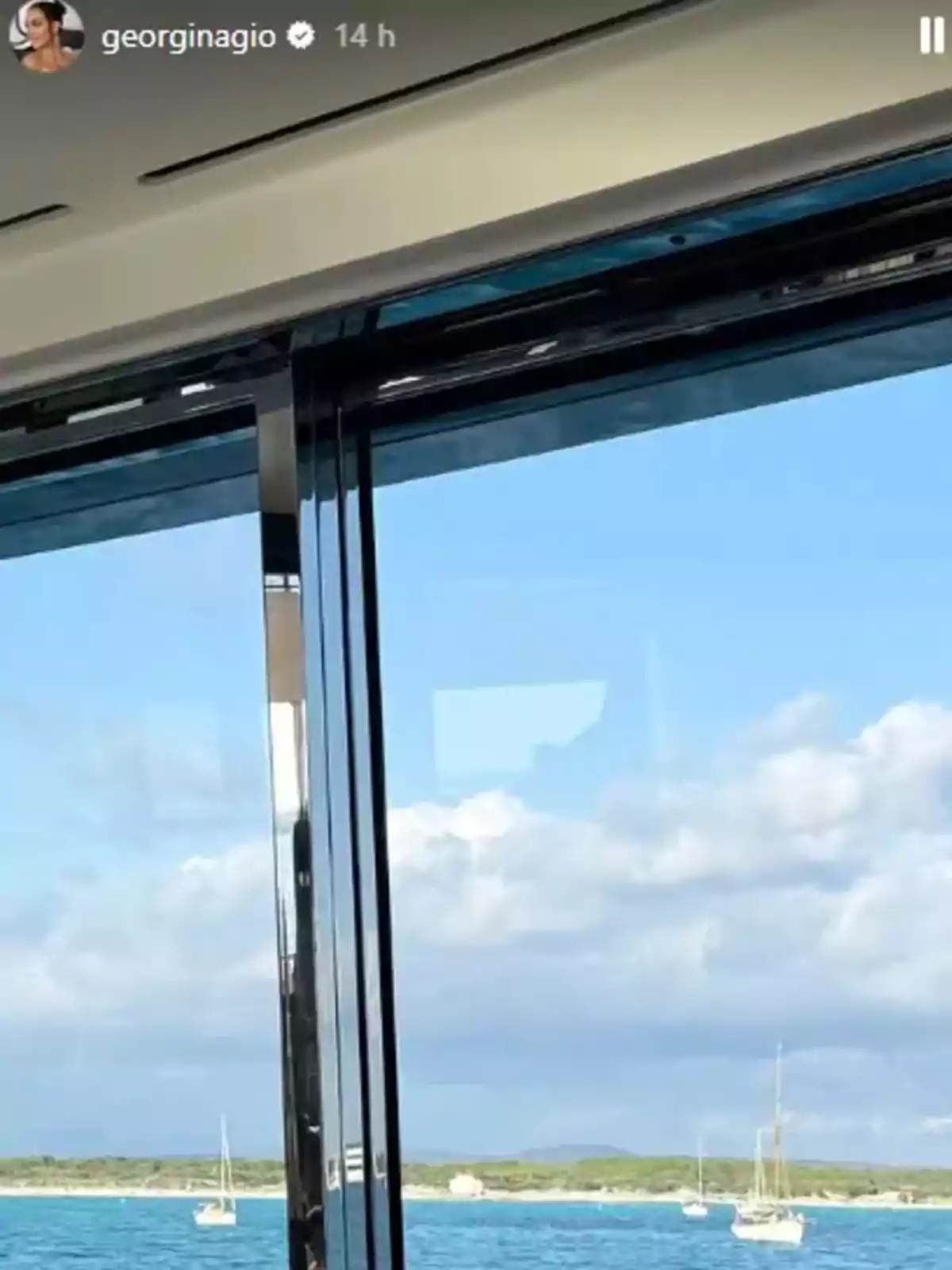 Vista desde el interior de un yate hacia el mar con veleros y cielo azul con nubes Vista desde el interior de un yate hacia el mar con veleros y cielo azul con nubes