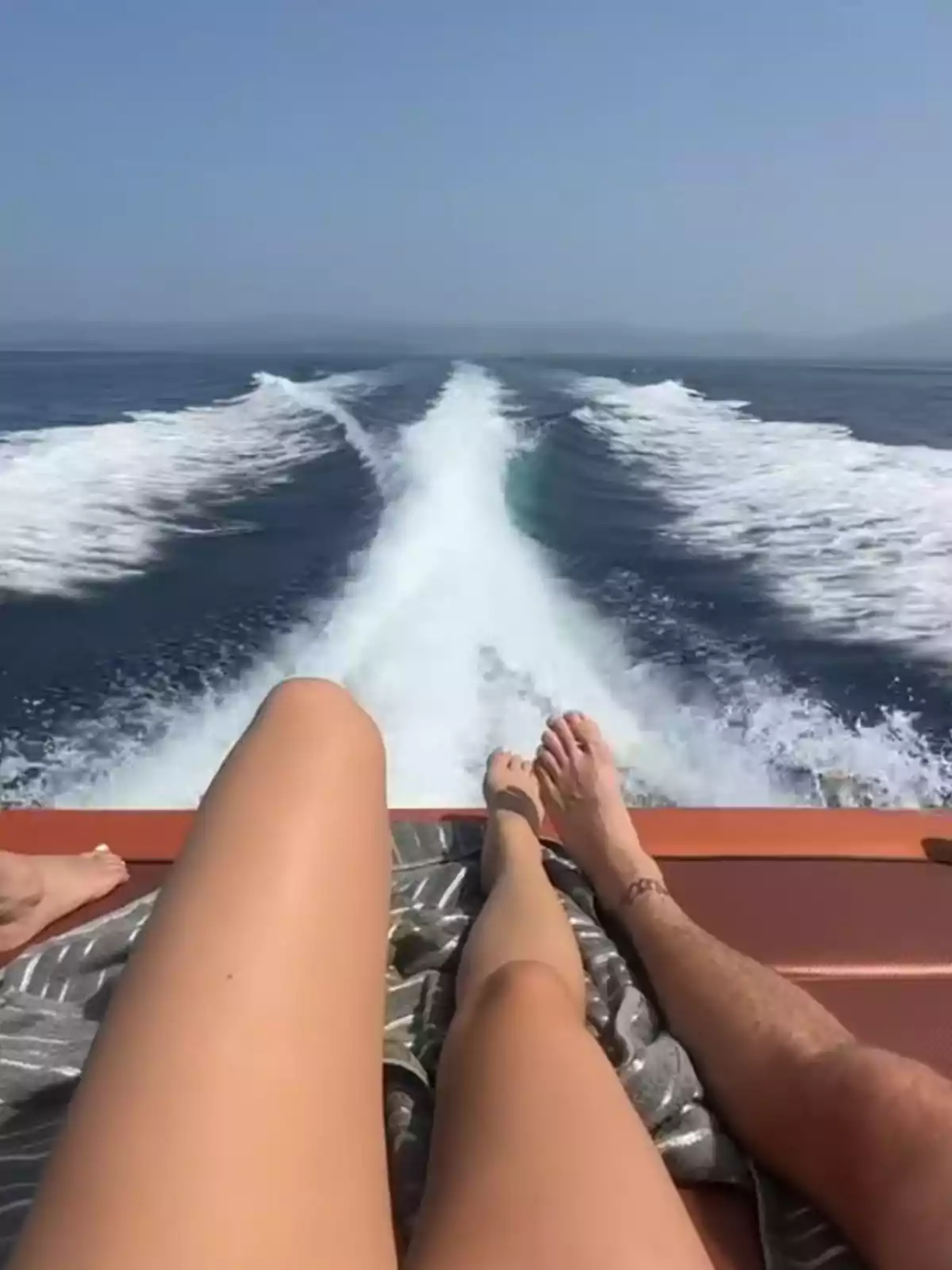 People lying in the back of a boat enjoying the sun while cruising on the sea, leaving a trail of water behind. People lying in the back of a boat enjoying the sun while cruising on the sea, leaving a trail of water behind.
