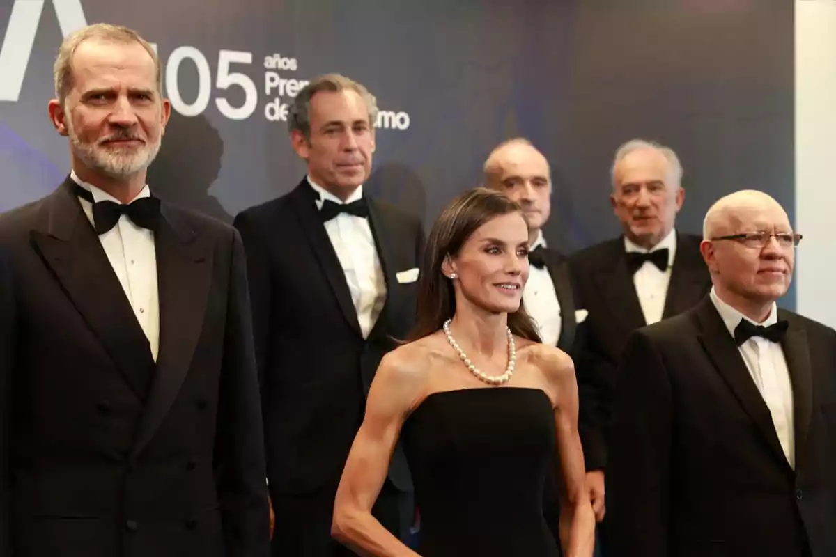 Group of elegantly dressed people in formal suits and gowns posing for a photo at a special event