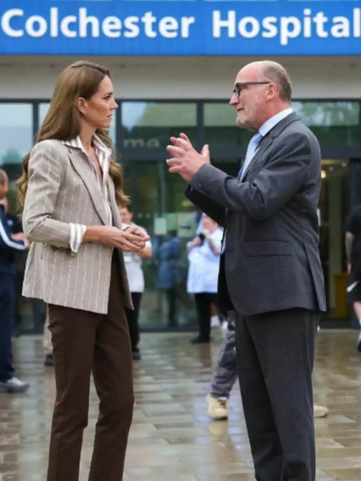 Kate Middleton y un hombre conversan frente a la entrada de un hospital llamado Colchester Hospital. Kate Middleton y un hombre conversan frente a la entrada de un hospital llamado Colchester Hospital.