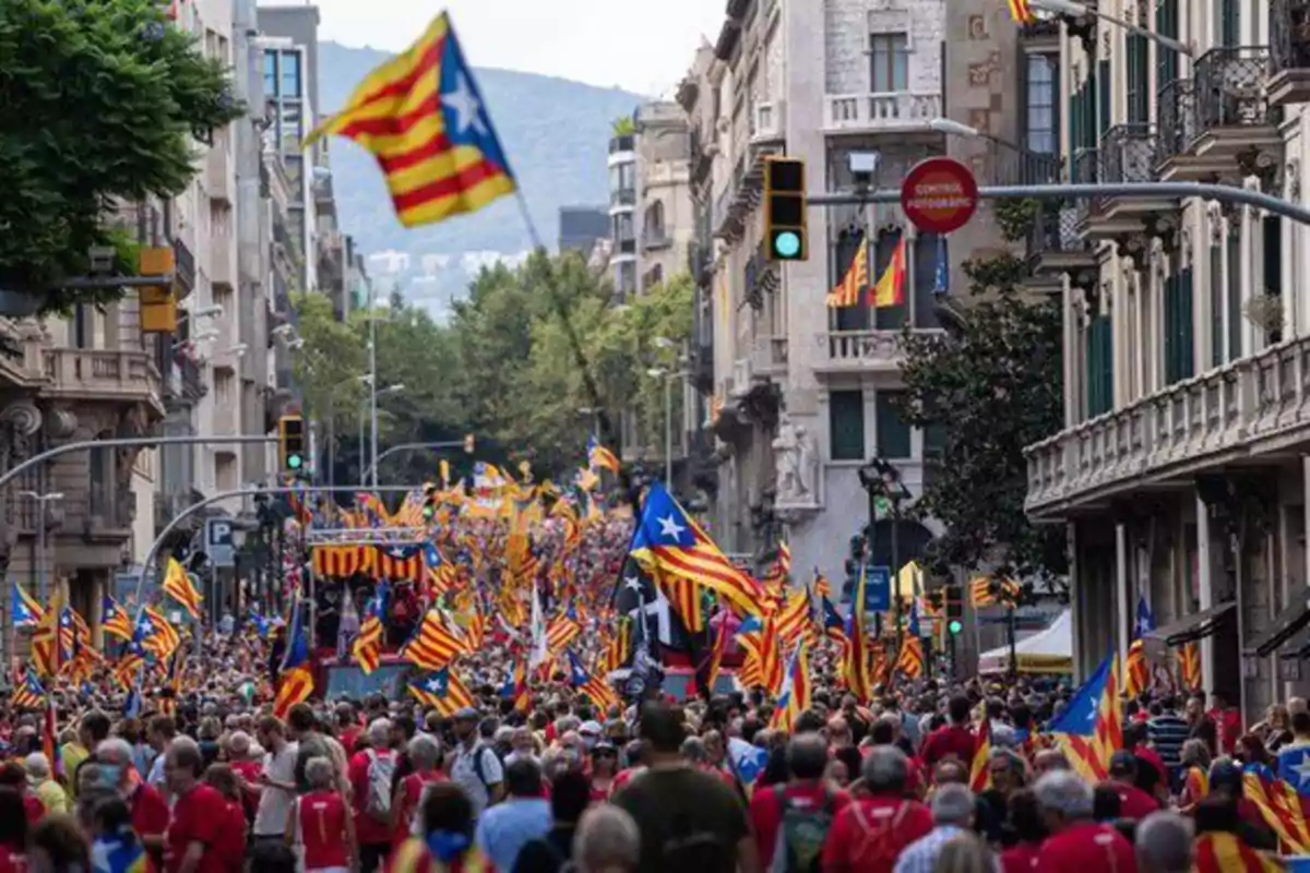 Multitud de personas marchando por una calle de la ciudad con numerosas banderas esteladas ondeando entre los edificios