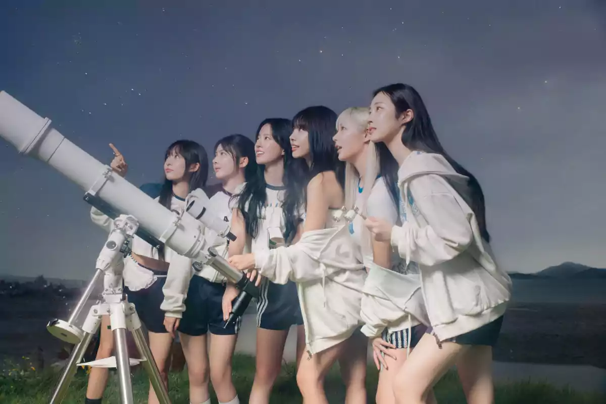 Siete chicas observan el cielo nocturno junto a un telescopio en un campo abierto