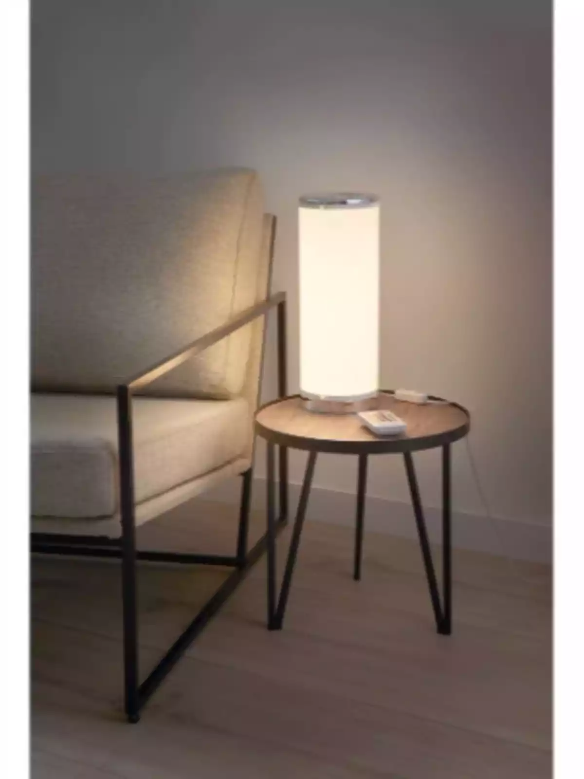 Sillón beige junto a una mesa redonda de madera con una lámpara encendida Sillón beige junto a una mesa redonda de madera con una lámpara encendida
