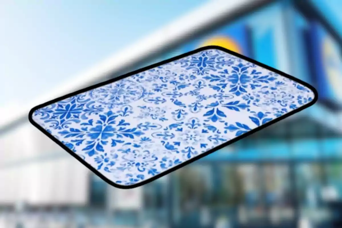 Tapete rectangular con diseño de flores azules sobre fondo blanco y borde negro frente a un edificio desenfocado Tapete rectangular con diseño de flores azules sobre fondo blanco y borde negro frente a un edificio desenfocado