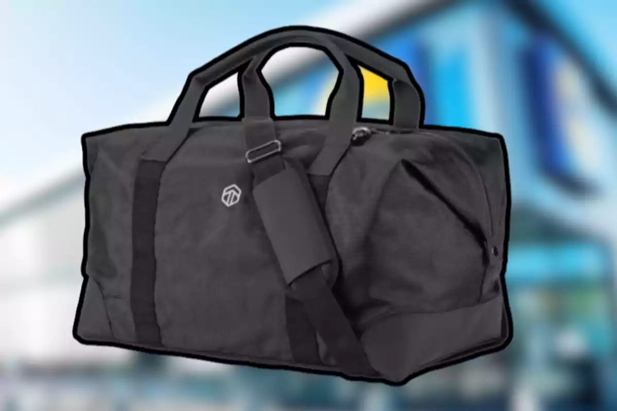 Bolsa deportiva negra con asas y correa ajustable sobre un fondo desenfocado Bolsa deportiva negra con asas y correa ajustable sobre un fondo desenfocado