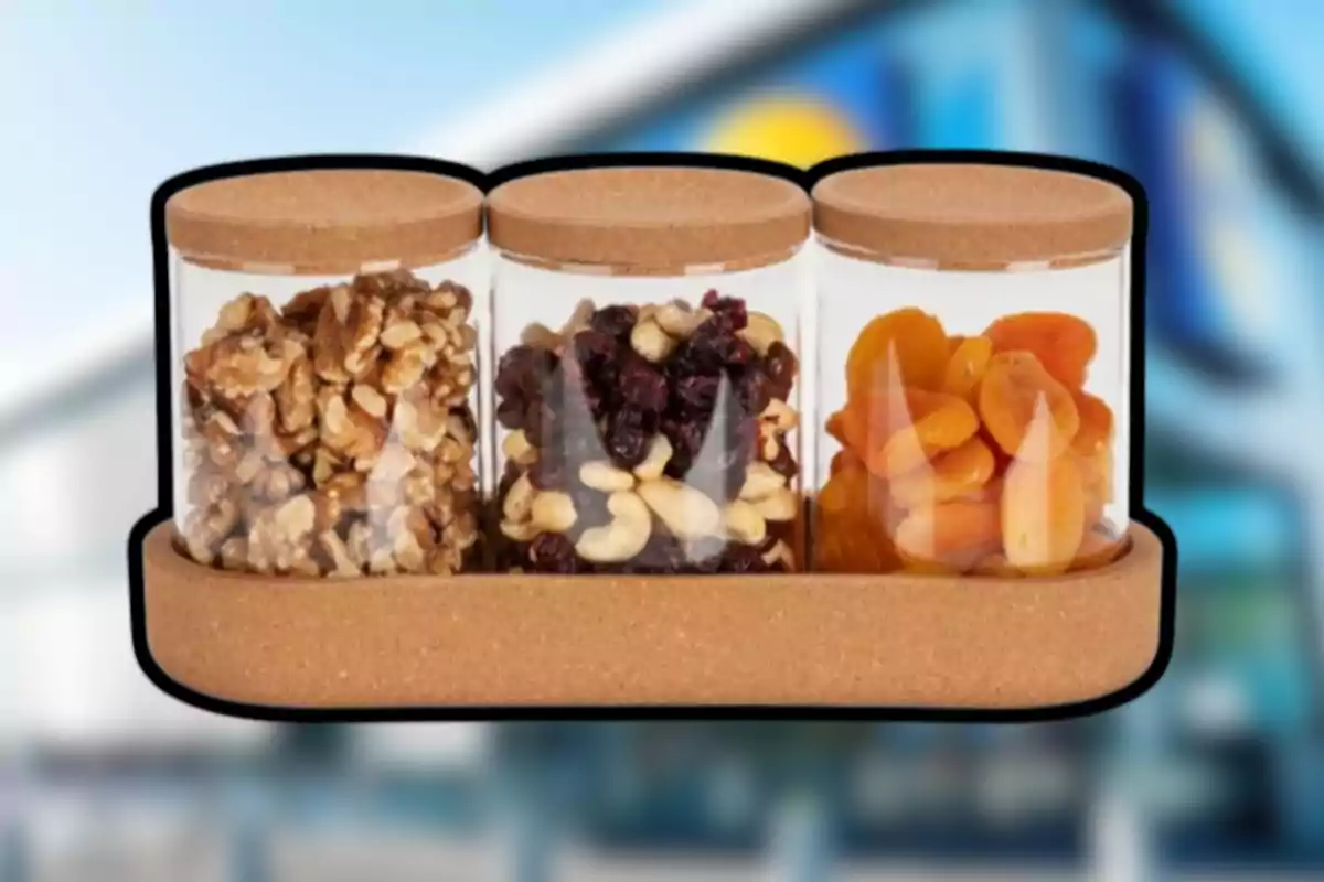Tres frascos de vidrio con tapa de corcho contienen nueces, mezcla de frutos secos y albaricoques deshidratados, todos colocados sobre una bandeja del mismo material. Tres frascos de vidrio con tapa de corcho contienen nueces, mezcla de frutos secos y albaricoques deshidratados, todos colocados sobre una bandeja del mismo material.