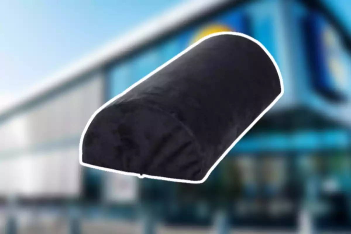 Cojín ortopédico negro con forma semicilíndrica sobre un fondo de edificio desenfocado Cojín ortopédico negro con forma semicilíndrica sobre un fondo de edificio desenfocado