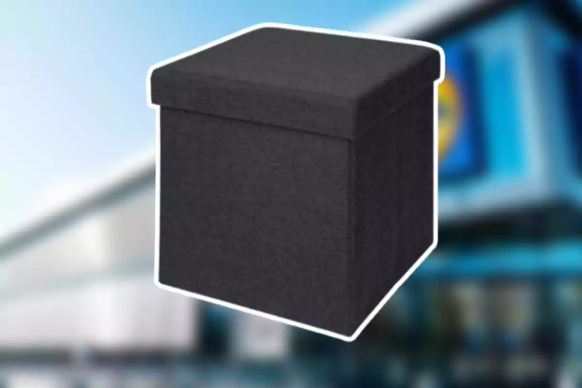 Un puff cuadrado de tela color negro frente a un fondo desenfocado de una tienda Un puff cuadrado de tela color negro frente a un fondo desenfocado de una tienda