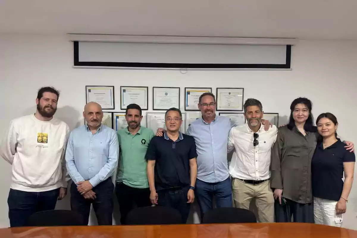Ocho personas posan juntas en una sala de reuniones frente a una pared con diplomas enmarcados