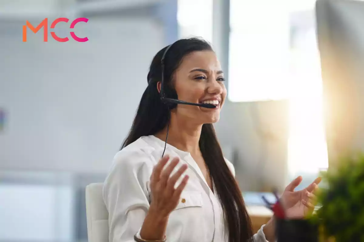 Mujer joven con auriculares y micrófono sonriendo mientras trabaja en una oficina moderna
