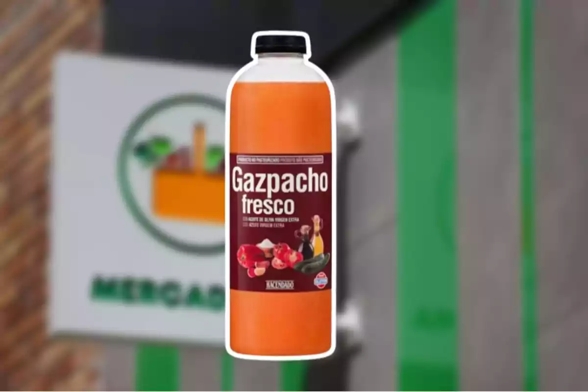 Botella de gazpacho fresco de la marca Hacendado frente a un cartel de supermercado desenfocado. Botella de gazpacho fresco de la marca Hacendado frente a un cartel de supermercado desenfocado.