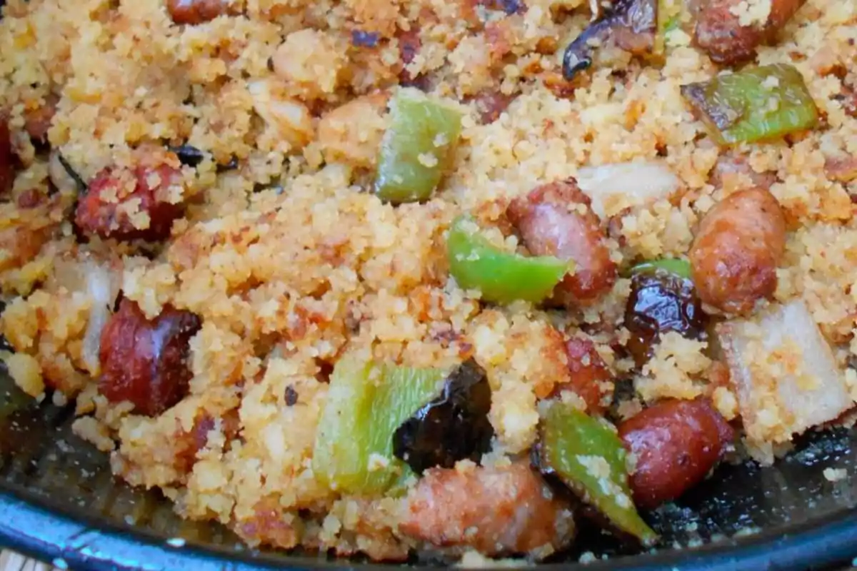 Plato de migas con chorizo, pimientos verdes y trozos de carne en sartén Plato de migas con chorizo, pimientos verdes y trozos de carne en sartén