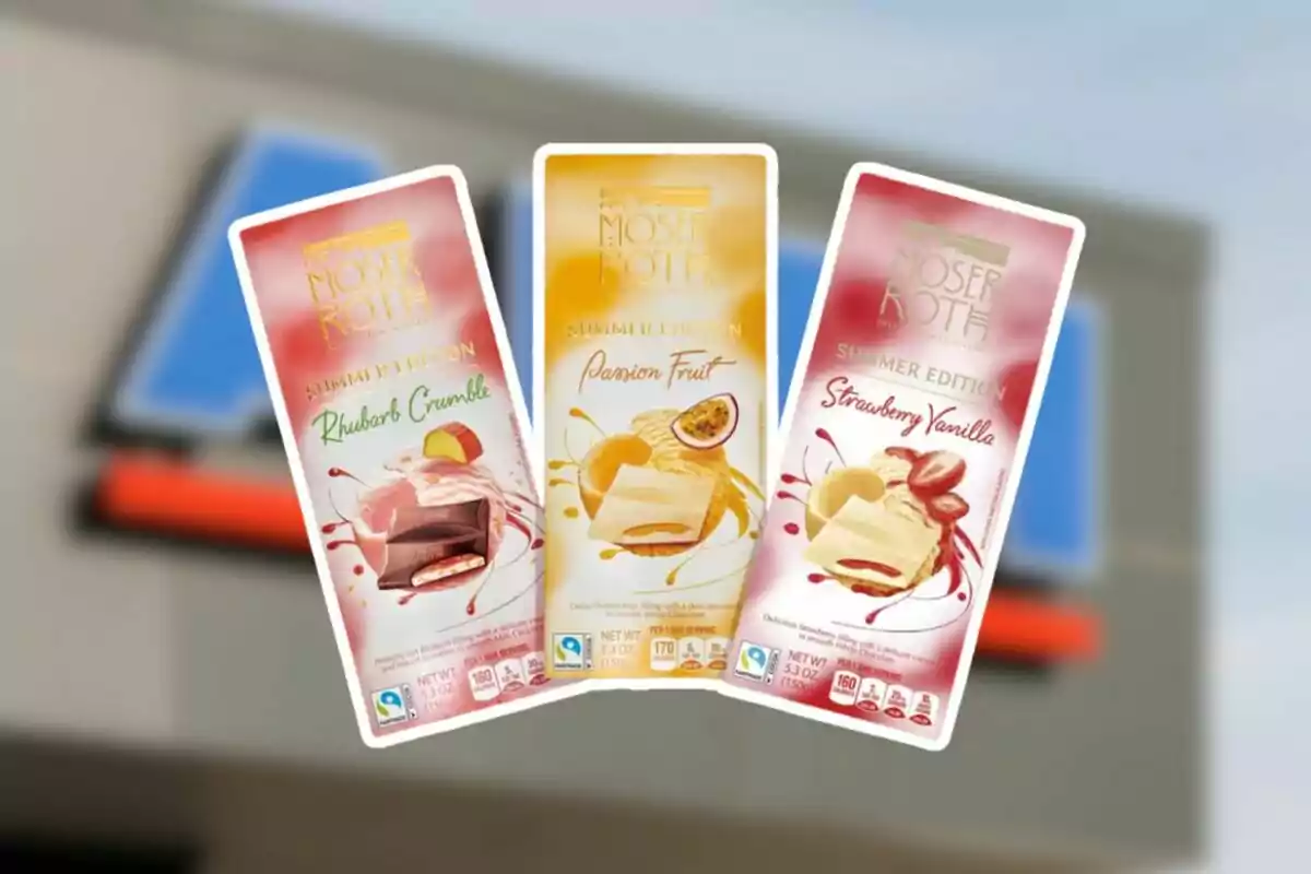 Three Moser Roth summer edition chocolate bars with rhubarb crumble, passion fruit, and vanilla with strawberry flavors in front of a blurred store background. Three Moser Roth summer edition chocolate bars with rhubarb crumble, passion fruit, and vanilla with strawberry flavors in front of a blurred store background.