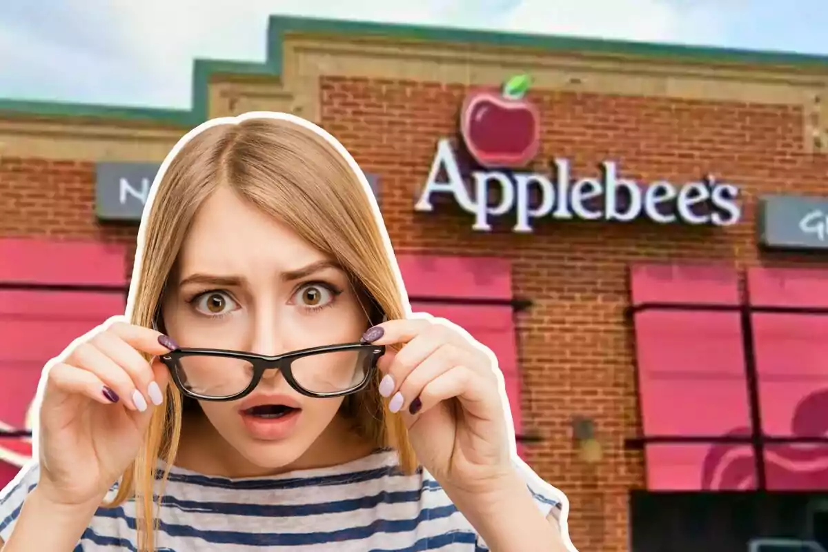 Young woman with a surprised expression holding her glasses in front of an Applebee's restaurant