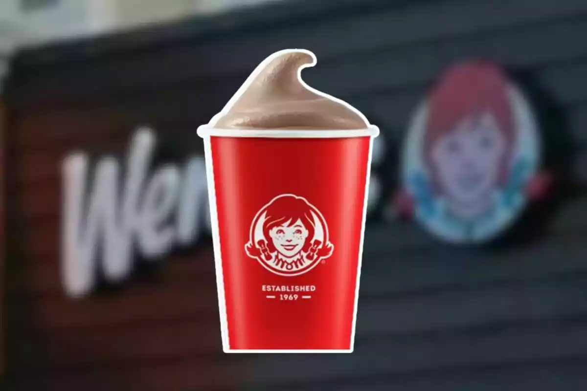 Vaso rojo de helado de chocolate de Wendy's con el logo de la marca al frente y fondo borroso del restaurante Vaso rojo de helado de chocolate de Wendy's con el logo de la marca al frente y fondo borroso del restaurante