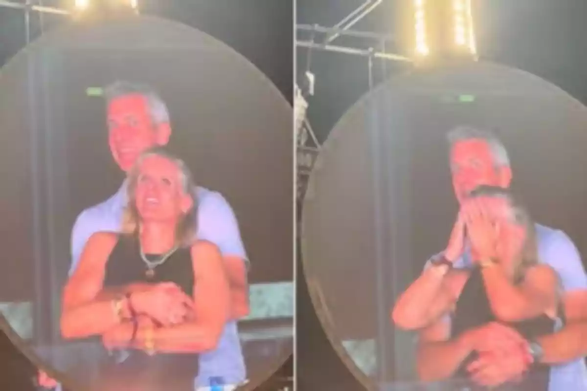 Una pareja abrazada aparece en una pantalla gigante durante un evento, la mujer primero sonríe y luego se cubre el rostro con las manos mientras el hombre la sostiene por detrás Una pareja abrazada aparece en una pantalla gigante durante un evento, la mujer primero sonríe y luego se cubre el rostro con las manos mientras el hombre la sostiene por detrás