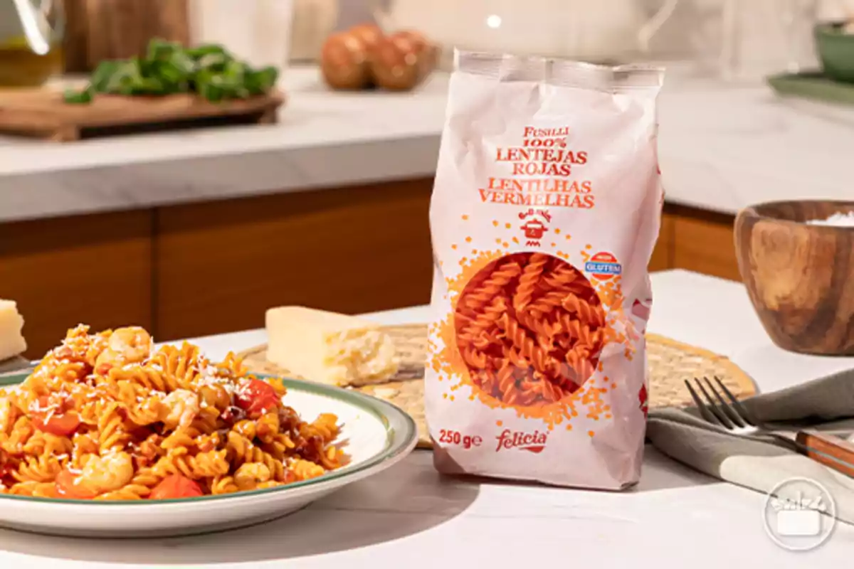 Paquete de fusilli de lentejas rojas junto a un plato de pasta cocida con camarones y queso rallado en una cocina moderna Paquete de fusilli de lentejas rojas junto a un plato de pasta cocida con camarones y queso rallado en una cocina moderna