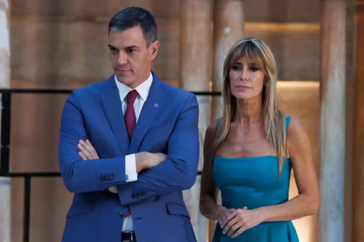 Pedro Sánchez con traje azul y corbata roja está de pie junto a Begoña Gómez con vestido azul turquesa en un entorno elegante con columnas de fondo Pedro Sánchez con traje azul y corbata roja está de pie junto a Begoña Gómez con vestido azul turquesa en un entorno elegante con columnas de fondo