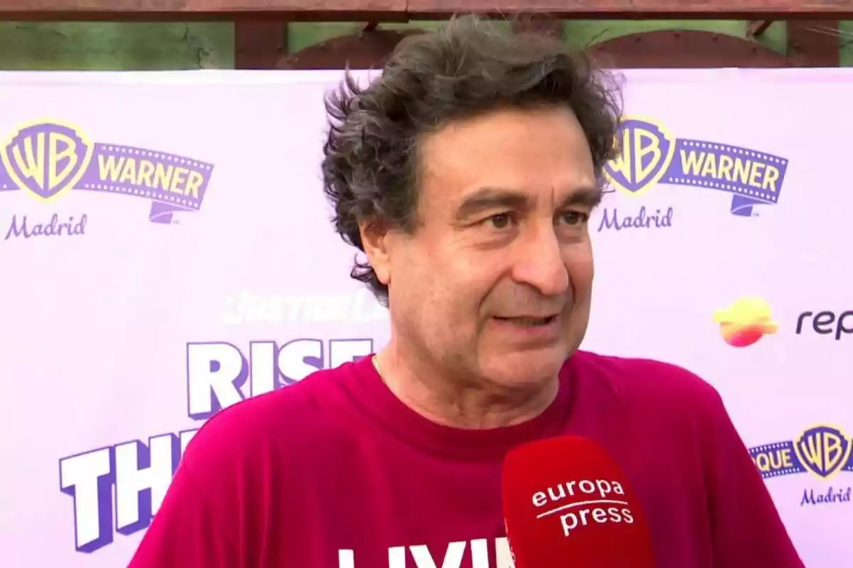 Pepe Rodríguez con camiseta fucsia siendo entrevistado por un micrófono rojo de europa press frente a un fondo con logotipos de Warner Madrid. Pepe Rodríguez con camiseta fucsia siendo entrevistado por un micrófono rojo de europa press frente a un fondo con logotipos de Warner Madrid.