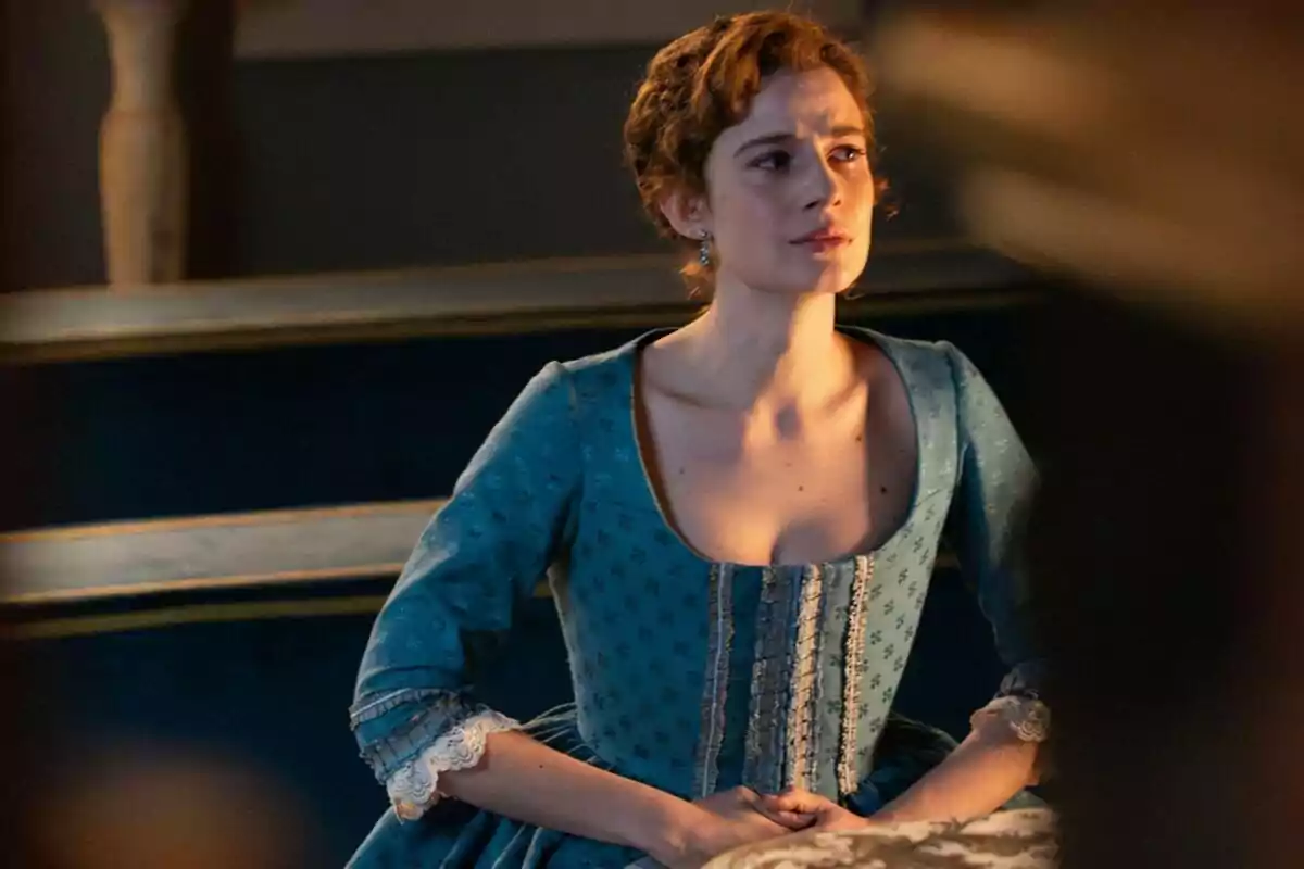 Rocío Suárez de Puga, embarazada, con expresión seria vestida con un vestido azul de época sentada en un banco antiguo. Rocío Suárez de Puga, embarazada, con expresión seria vestida con un vestido azul de época sentada en un banco antiguo.