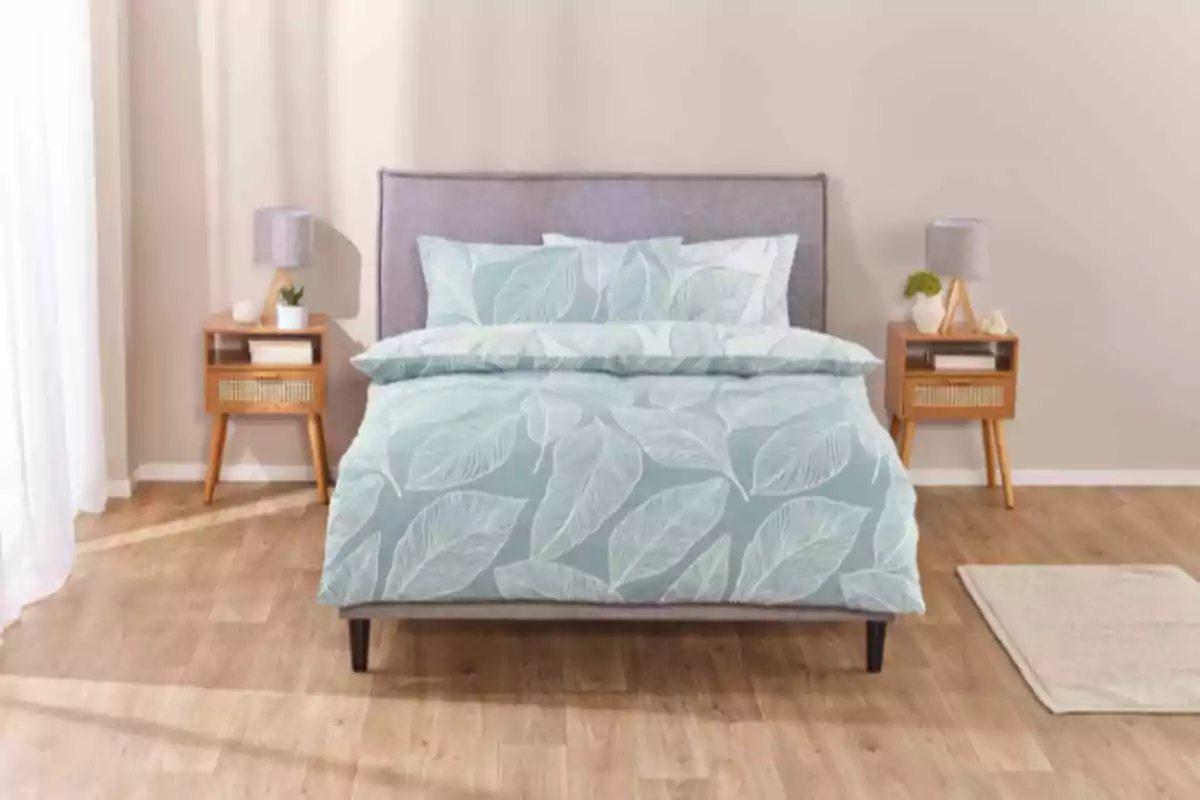 Cama con edredón azul de hojas blancas en un dormitorio moderno con dos burós de madera y lámparas grises Cama con edredón azul de hojas blancas en un dormitorio moderno con dos burós de madera y lámparas grises